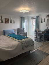 Bedroom with wood finished floors, wooden walls, and a decorative wall