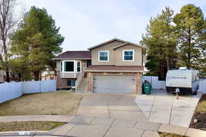 View of front facade featuring concrete driveway, brick siding, a garage, stairway, and roof with shingles