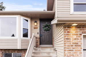 Doorway to property with brick siding and a garage