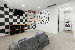 Living area featuring light colored carpet, washer and dryer, recessed lighting, and an accent wall