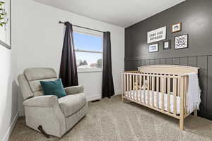 Bedroom featuring a crib and carpet floors