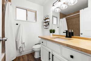 Full bathroom featuring a butcher block vanity and wood finished floors