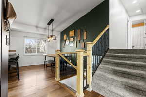 Stairs with wood finished floors and a chandelier