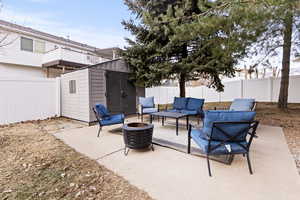 Fenced backyard with an outdoor living space with a fire pit, a storage shed, and a patio area