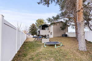 Rear view of house featuring a fenced backyard, a trampoline, a playground, a gate, and a shed
