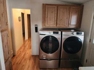 Laundry room featuring light wood-type flooring, cabinet space, and washer and clothes dryer