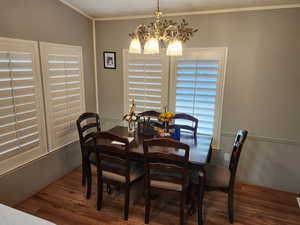 Dining space with ornamental molding, dark wood-style flooring, and a chandelier