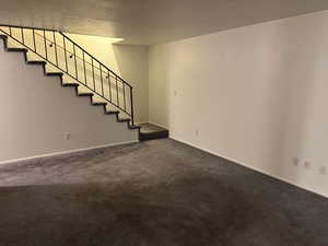 Basement with stairway and dark carpet