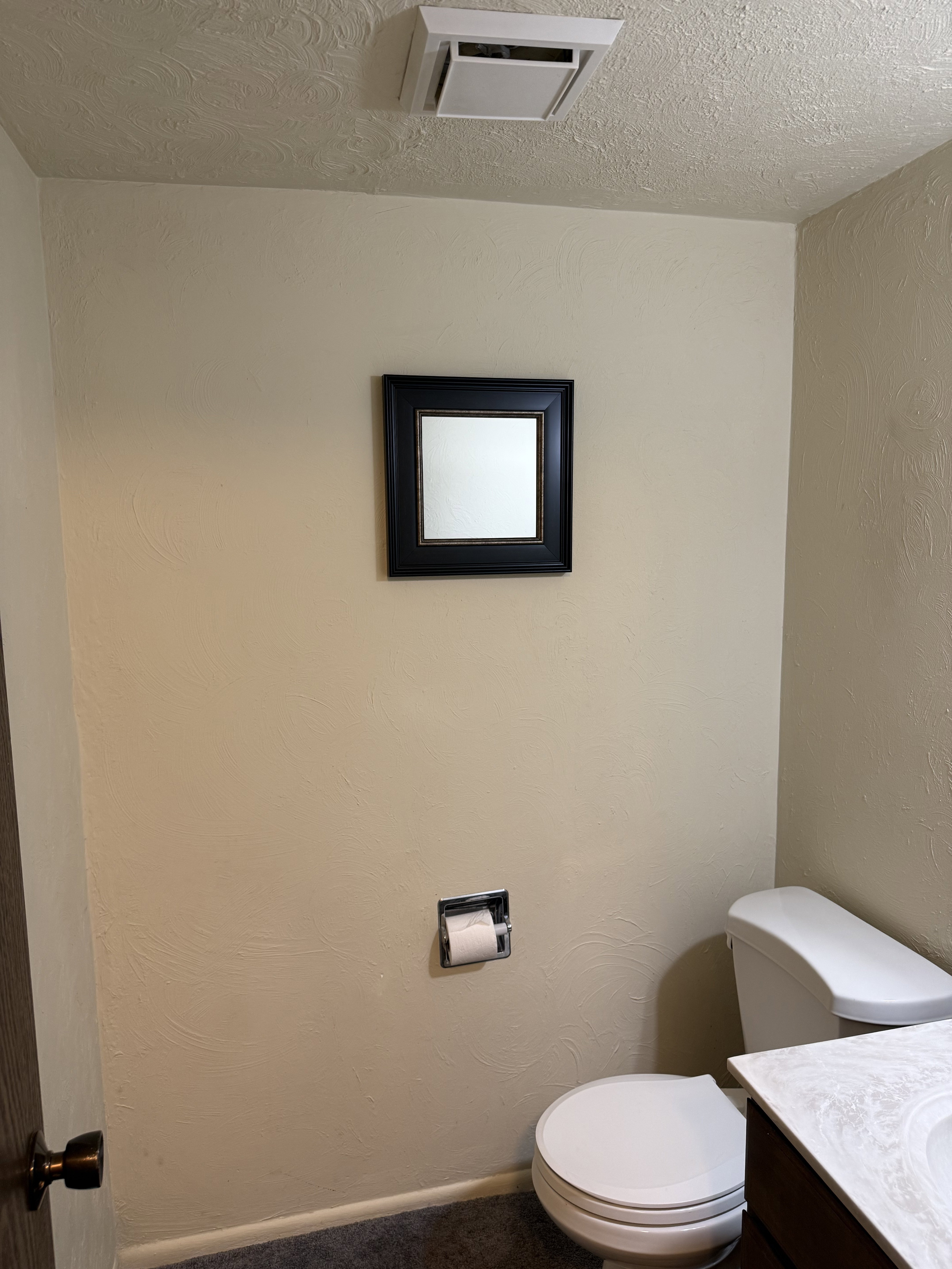 Bathroom featuring a textured ceiling, vanity, and a textured wall
