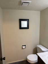 Bathroom featuring a textured ceiling, vanity, and a textured wall