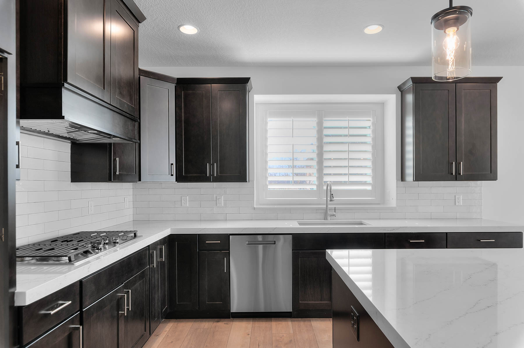 Kitchen featuring stainless steel appliances, decorative backsplash, light wood-style flooring, and light stone counters