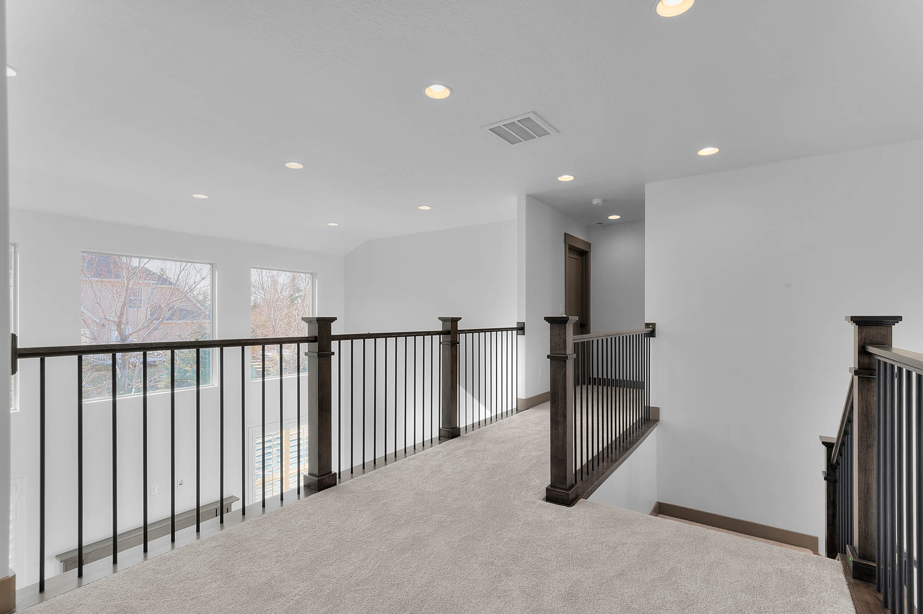 Hallway with carpet, recessed lighting, and an upstairs landing