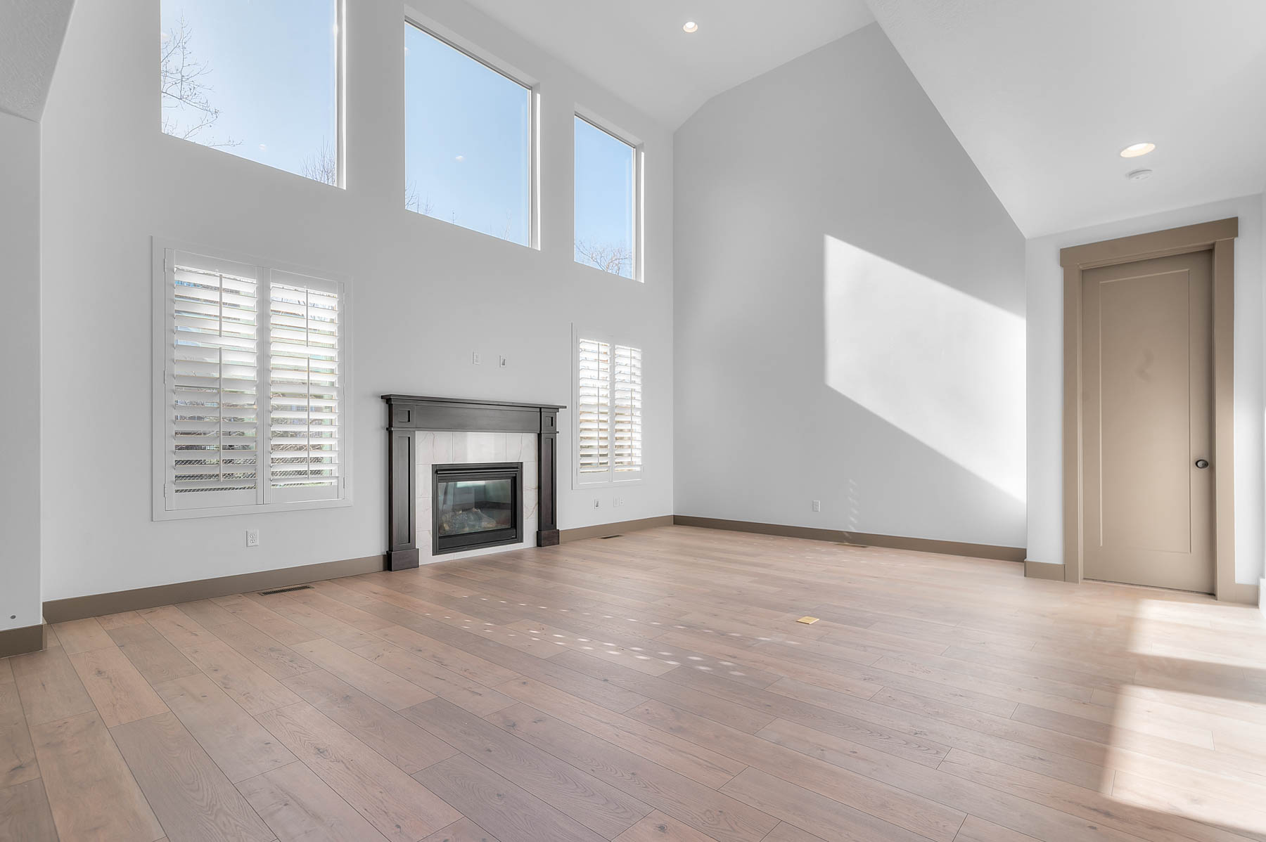 Unfurnished living room featuring a glass covered fireplace, light wood-style floors, vaulted ceiling, and recessed lighting