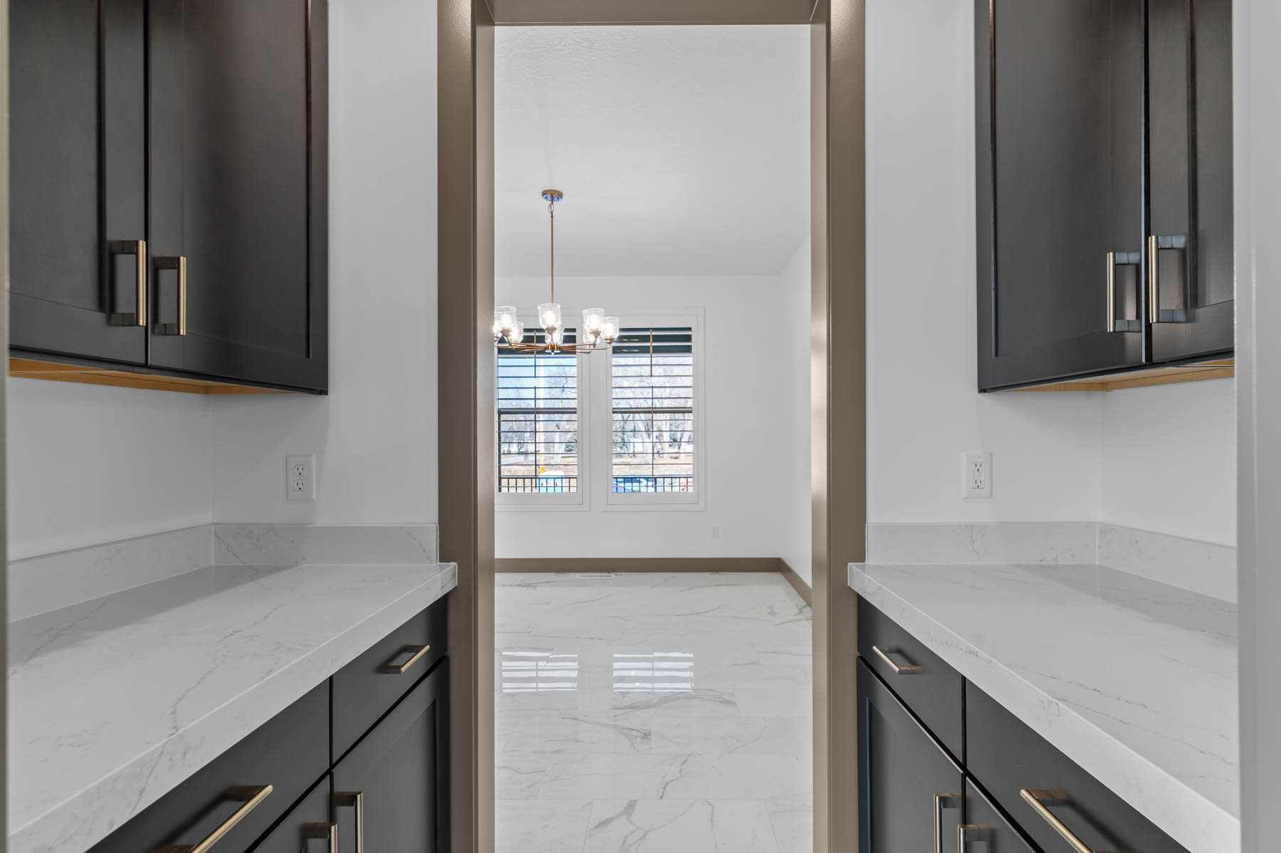 Kitchen featuring light stone counters, light marble finish floors, and hanging lights