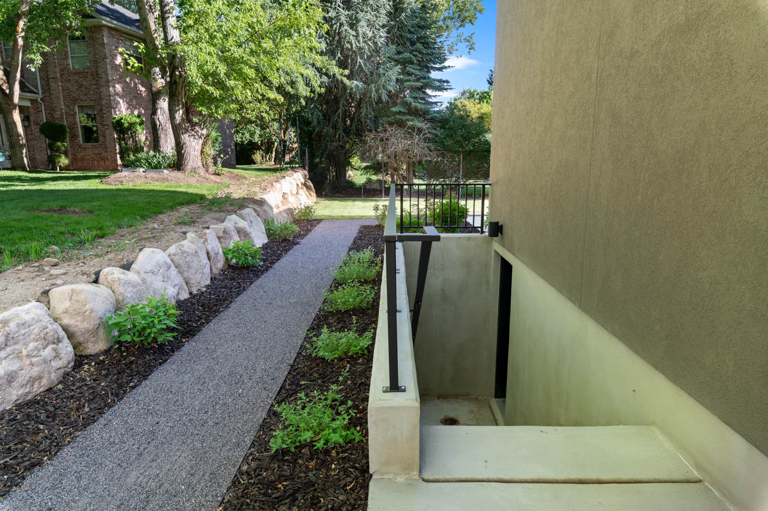 Exterior stucco finish with a concrete walkway leading to a subterranean entrance