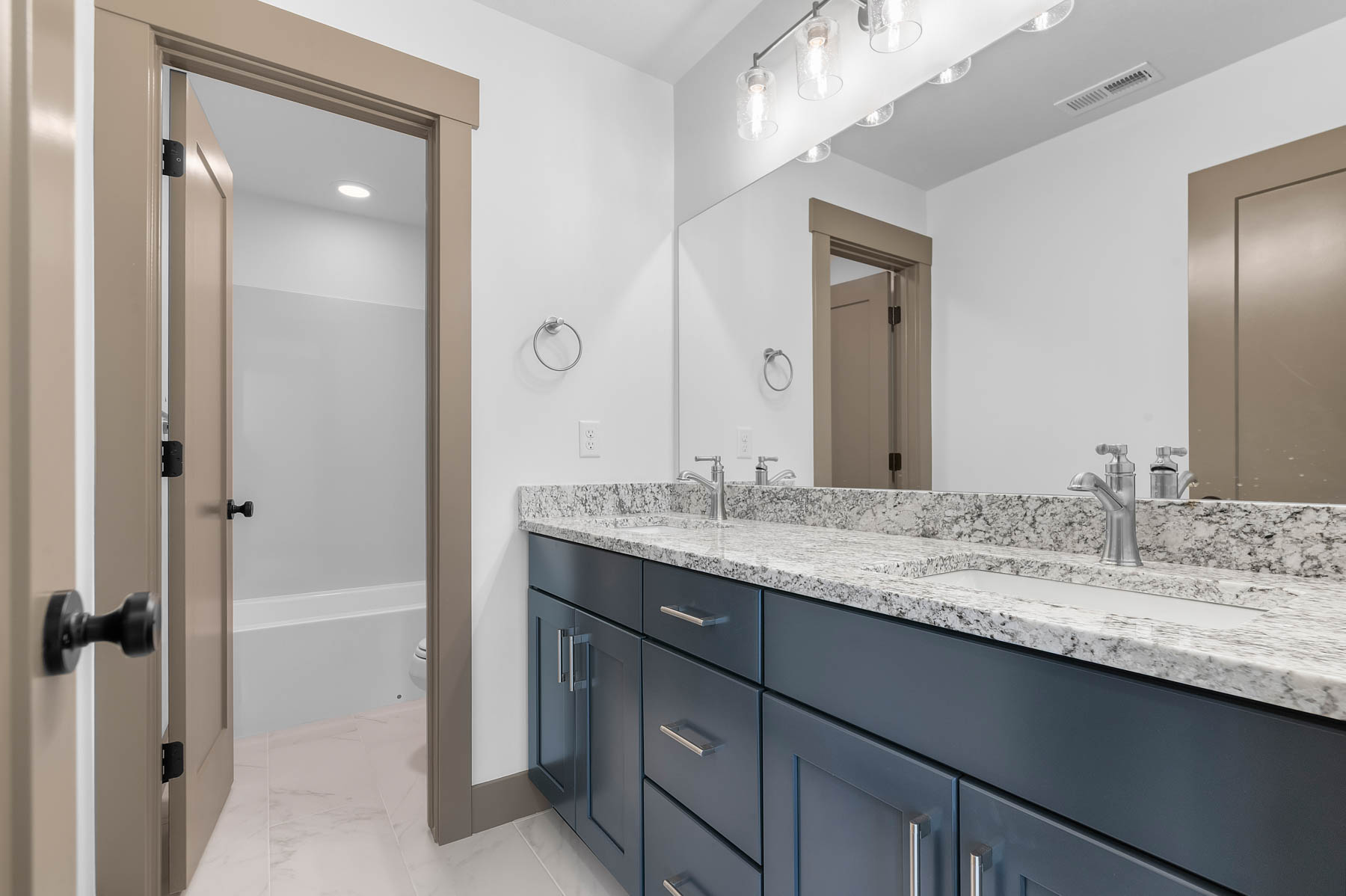 Full bathroom featuring double vanity, shower / washtub combination, and light marble finish floors