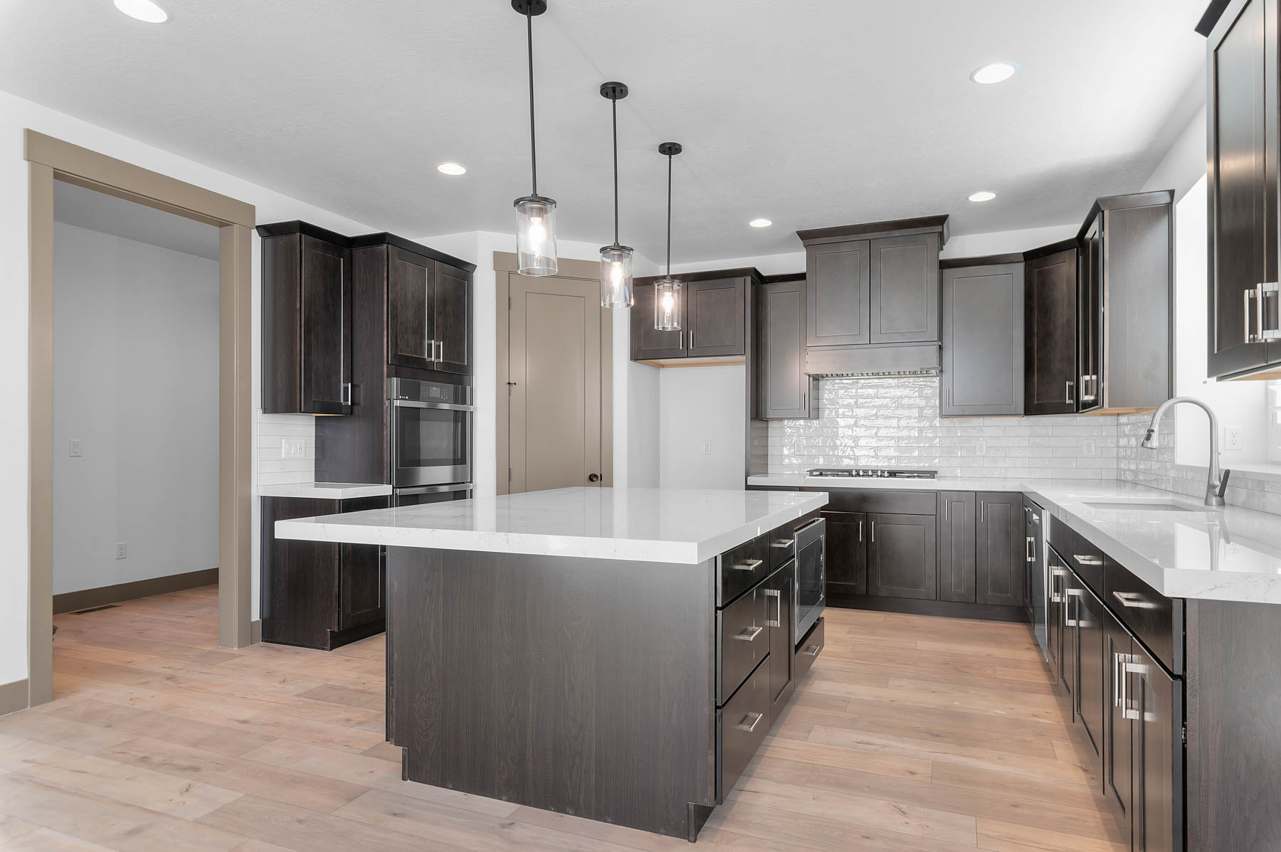 Kitchen with pendant lighting, light stone countertops, a center island, and light wood-style flooring