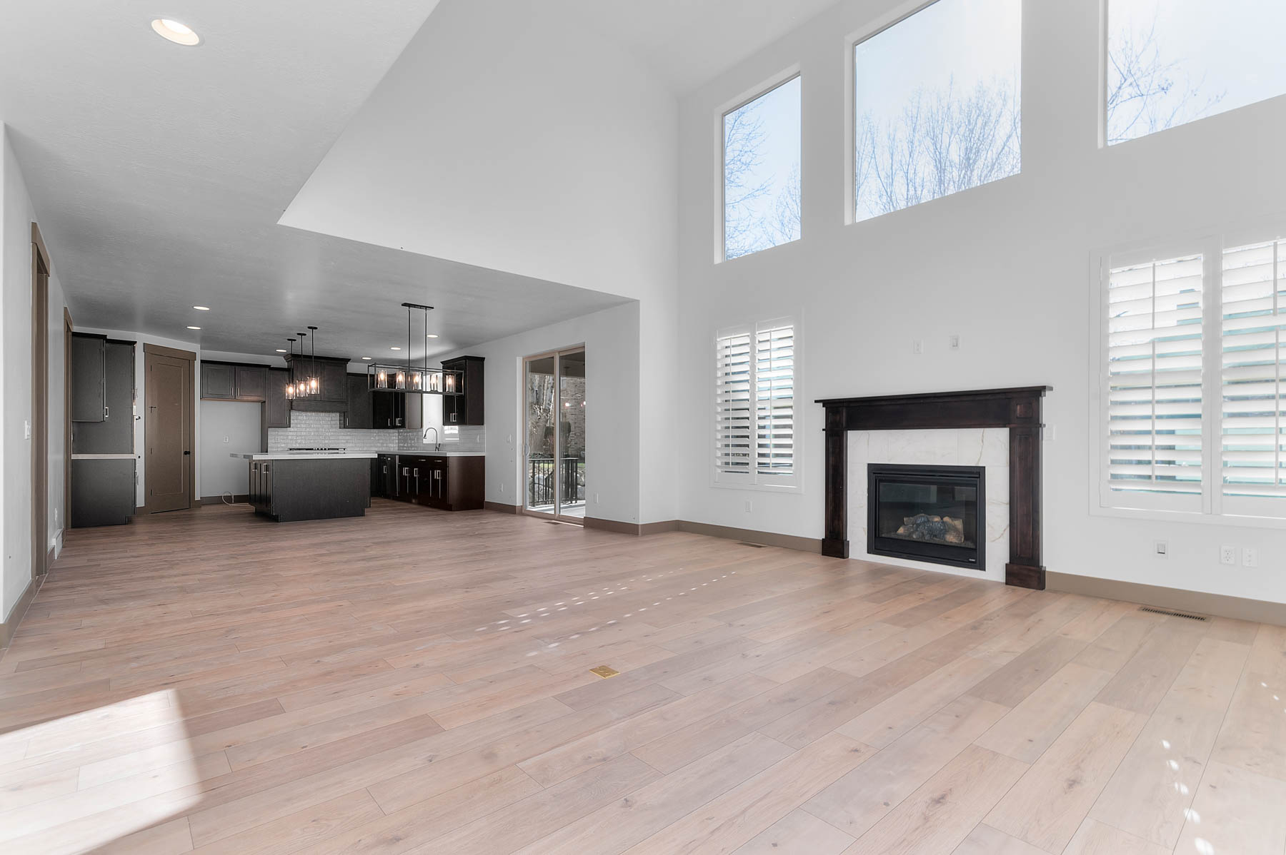 Unfurnished living room featuring a tile fireplace, light wood-style flooring, recessed lighting, and a high ceiling