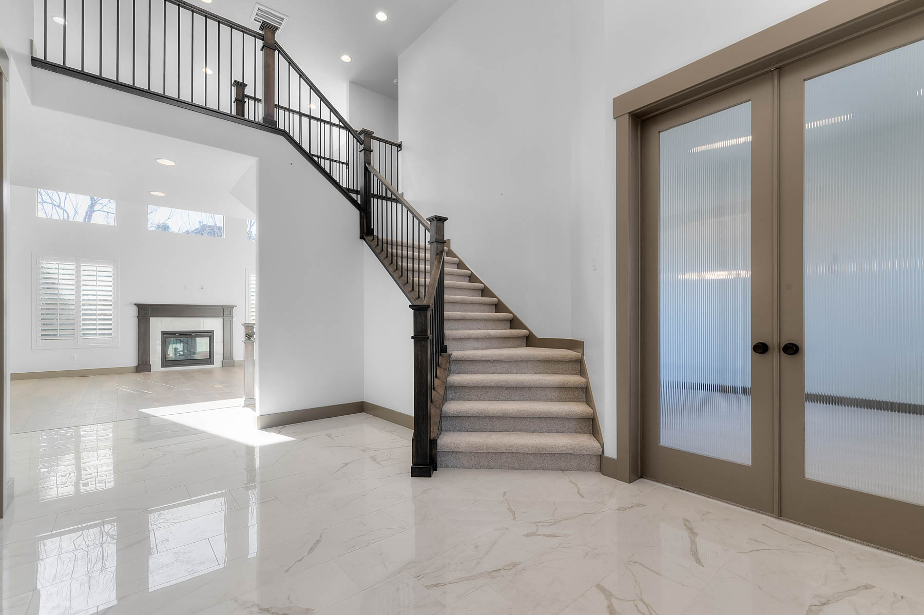 Stairs featuring french doors, a high ceiling, a premium fireplace, recessed lighting, and marble tiled floors