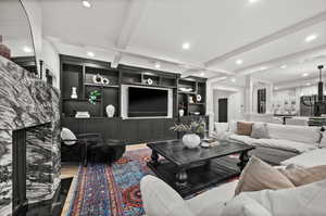 Living area featuring beam ceiling, recessed lighting, wood finished floors, built in features, and a fireplace