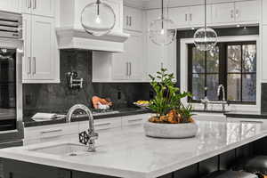 Kitchen featuring a kitchen breakfast bar, white cabinetry, dark stone counters, and an island with sink