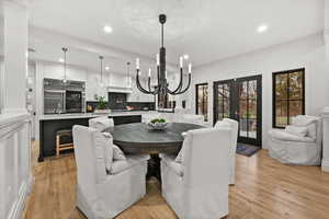 Dining room featuring french doors, light wood-style floors, a chandelier, and recessed lighting