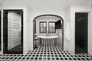 Master full bathroom with a freestanding tub, a stall shower, and tile walls