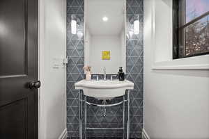 Half bathroom featuring tile walls and a sink