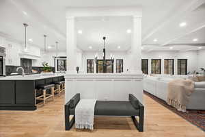 Living room with a chandelier, light wood-style flooring, recessed lighting, and beamed ceiling