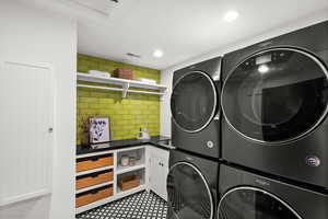 Washroom with stacked washer and clothes dryer and recessed lighting