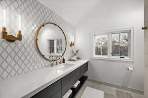 Bathroom featuring vanity, lofted ceiling, and light tile patterned flooring