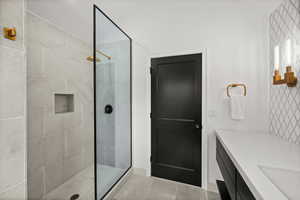 Bathroom with a walk in shower, vanity, and light tile patterned flooring