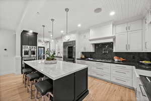 Kitchen with dark cabinetry, a breakfast bar area, dark stone countertops, recessed lighting, and hanging light fixtures