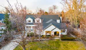 View of front of property featuring covered porch, roof with shingles, a front yard, and a chimney