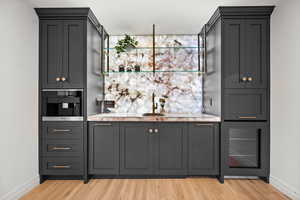 Master Bedroom lounge Indoor wet bar featuring light wood finished floors, gray cabinets, and stainless steel microwave