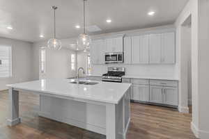 Kitchen featuring stainless steel appliances, recessed lighting, a kitchen island with sink, backsplash, and pendant lighting