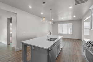Kitchen with decorative light fixtures, a center island with sink, appliances with stainless steel finishes, gray cabinets, and recessed lighting