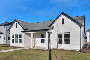 View of front facade featuring a shingled roof and a front lawn