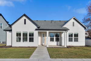 View of front of house featuring a front yard, roof with shingles, and covered porch