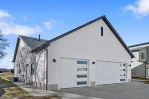 View of property exterior with driveway and roof with shingles