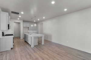 Kitchen featuring recessed lighting, a kitchen island with sink, stainless steel appliances, a kitchen bar, and hanging light fixtures