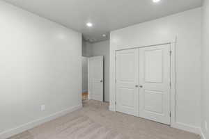 Unfurnished bedroom featuring light colored carpet, a closet, and recessed lighting