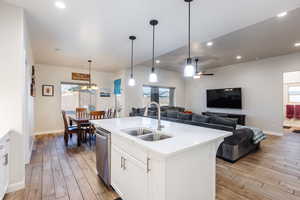 Kitchen with white cabinets, open floor plan, hanging light fixtures, light stone countertops, and recessed lighting