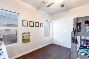 Bedroom with a closet, dark colored carpet, and ceiling fan