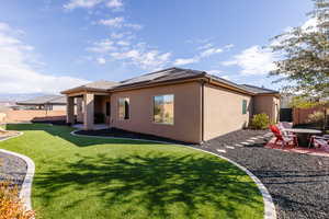Back of house with a patio area, a fenced backyard, and roof mounted solar panels