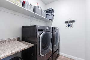 Laundry area with washing machine and clothes dryer and light wood-type flooring