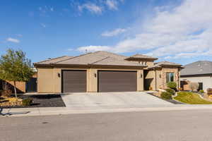 Prairie-style house featuring an attached garage, driveway, stucco siding, and a gate