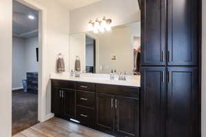 Full bath with double vanity and light wood-style flooring