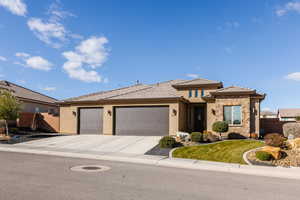 View of front of property featuring a garage, stone siding, concrete driveway, stucco siding, and a tile roof