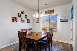 Dining area featuring dark wood-style flooring and a chandelier